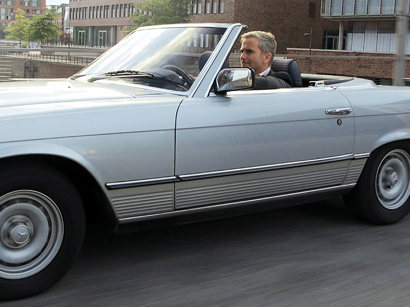 Mann genießt eine Fahrt in einem Cabriolet durch die Stadt